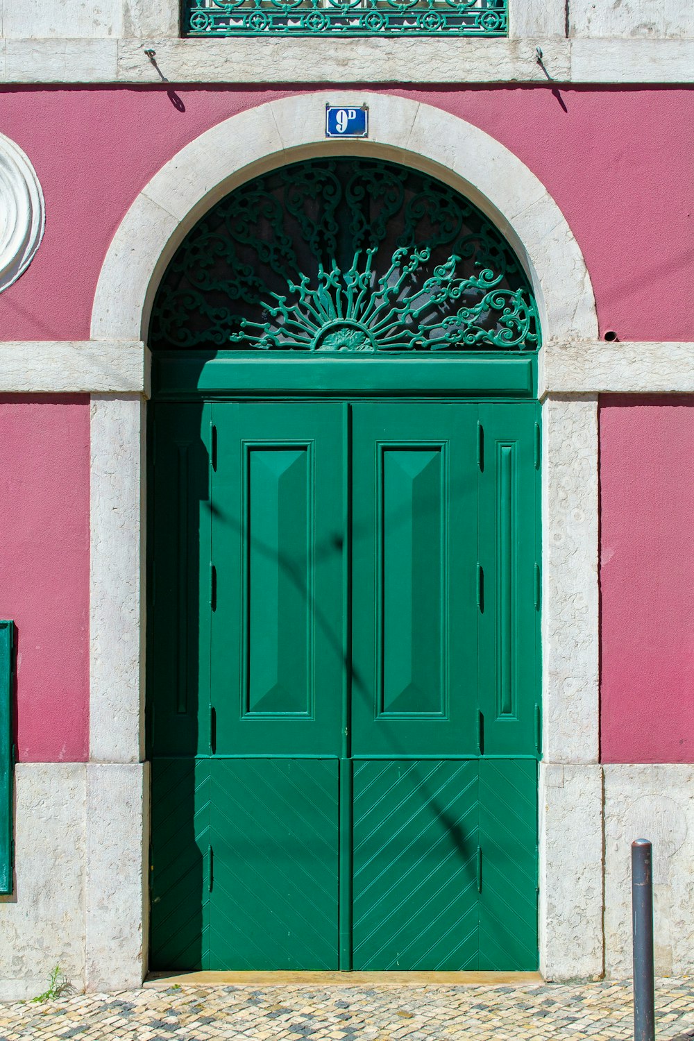 green wooden door on pink concrete wall