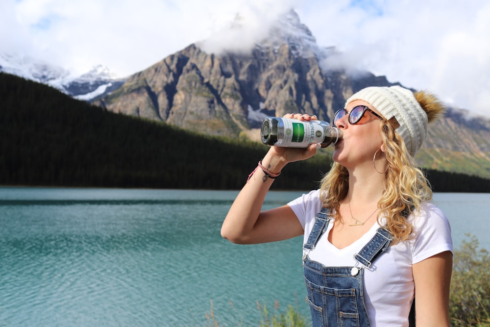 woman in white tank top drinking on green and black sports bottle