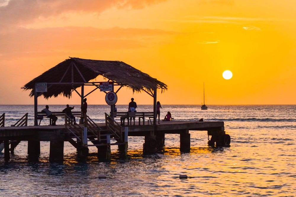 silhueta das pessoas na praia durante o pôr do sol