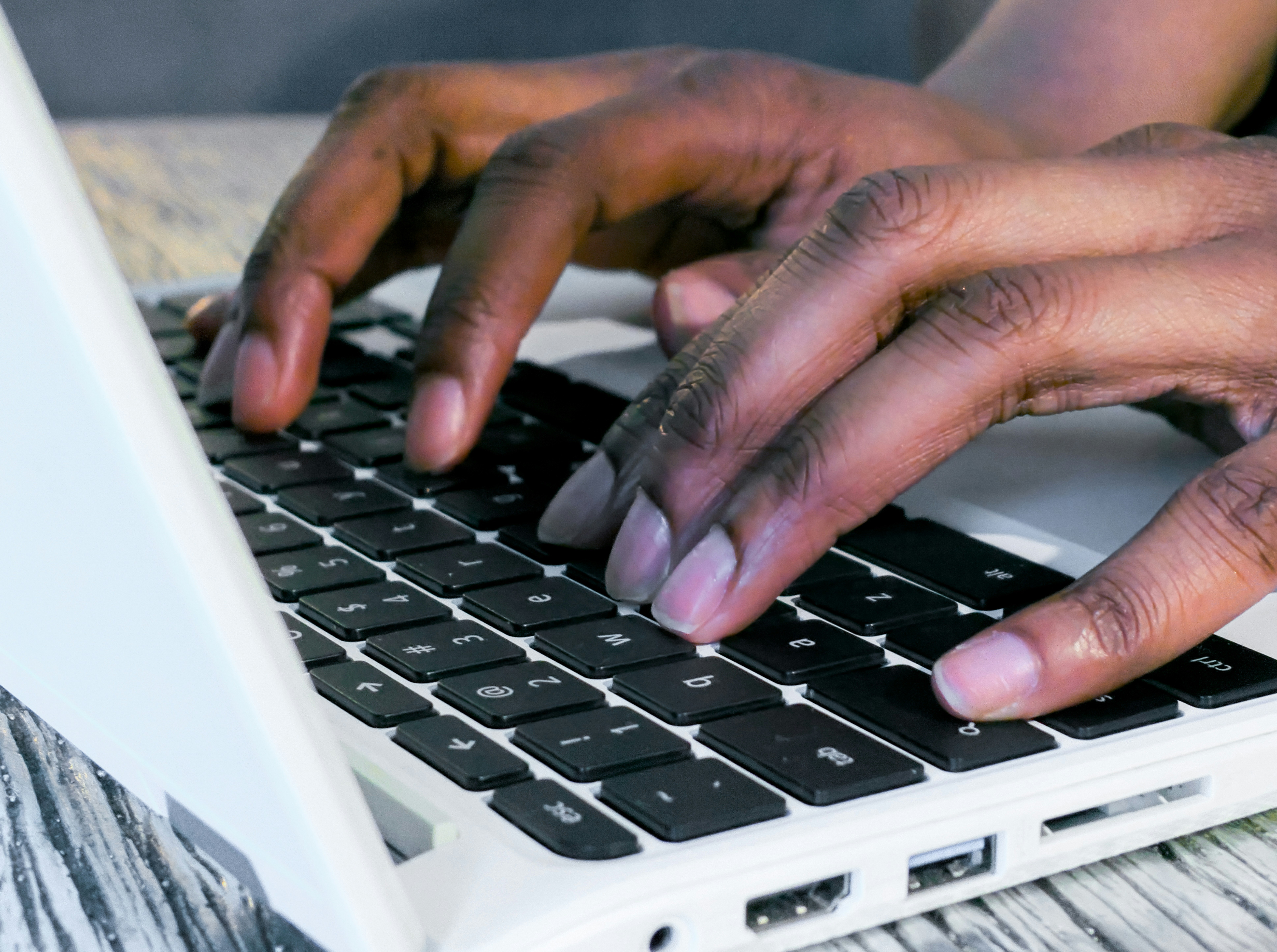 Close-up of hands typing on a laptop keyboard working on document preparation tasks