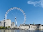 white ferris wheel near white concrete building under blue sky during daytime