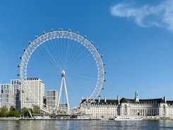white ferris wheel near white concrete building under blue sky during daytime