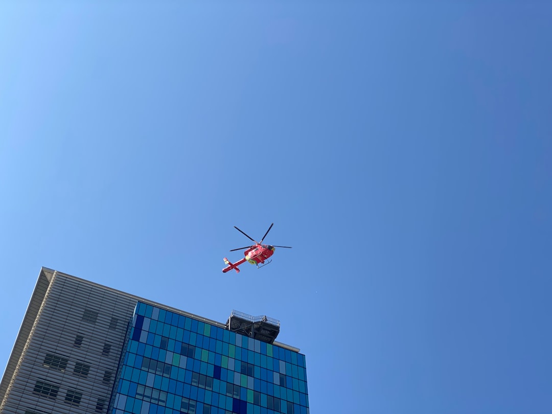 red and white helicopter flying over the building during daytime