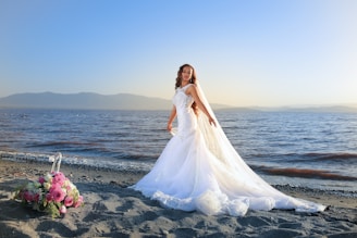 A bride glowing with natural makeup against a sunlit beach backdrop.