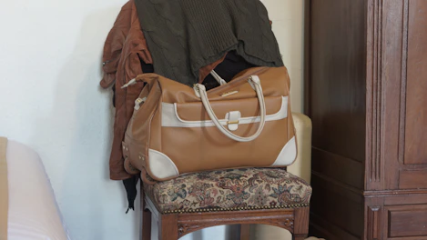 Close-up of a stylish leather-trimmed tote bag resting on a vintage chair.