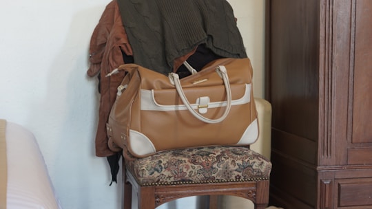 Compact leather crossbody bag hanging on a vintage chair in a cozy room
