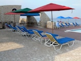 Outdoor pool area with lounge chairs and umbrellas.