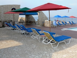 Outdoor pool area with lounge chairs and umbrellas.