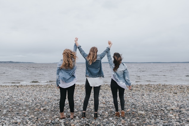 4 women standing on beach during daytime