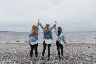 4 women standing on beach during daytime