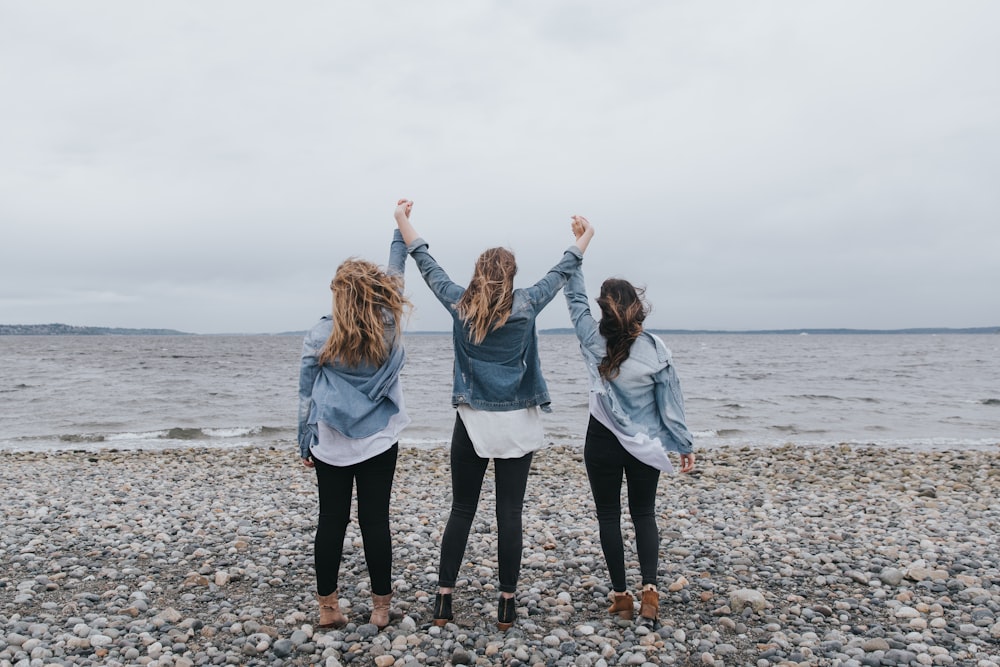 4 women standing on beach during daytime