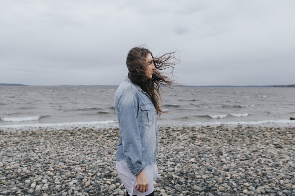 Frau in blauer Jeansjacke tagsüber am Strandufer