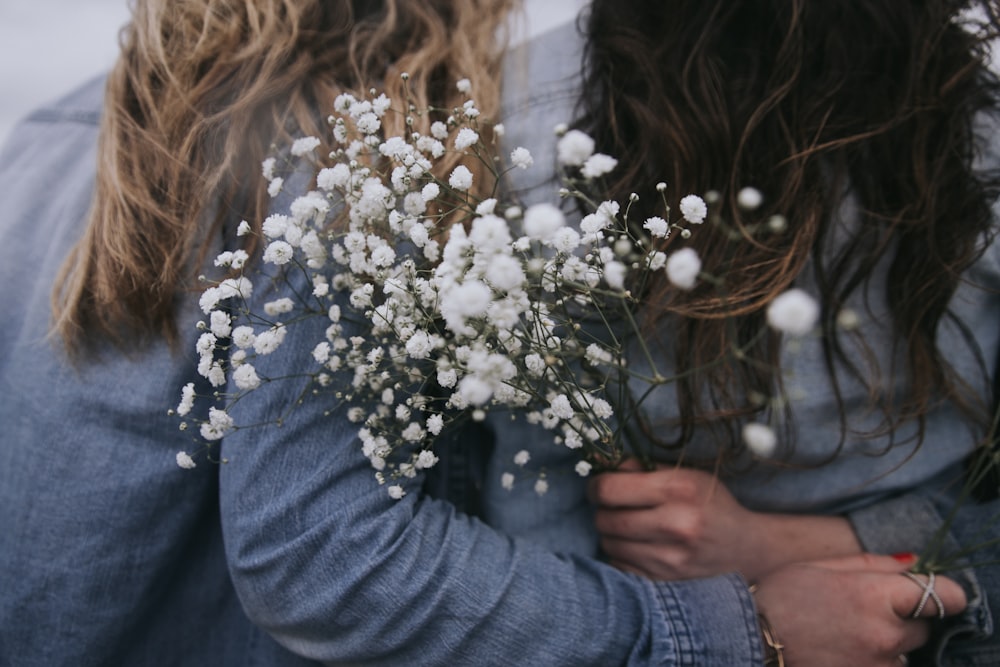 woman in gray long sleeve shirt holding white flowers