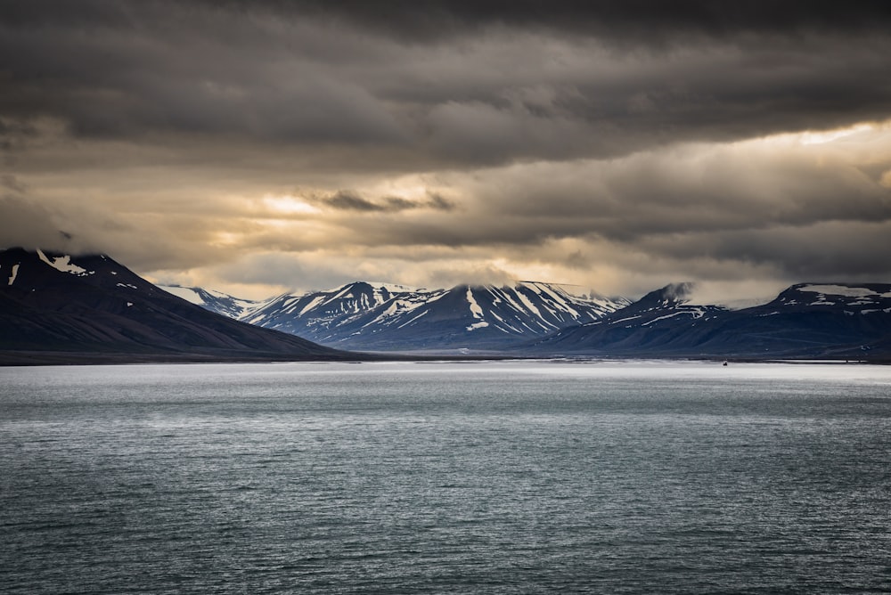 snow covered mountain near body of water during daytime