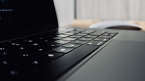 Close-up of hands typing on a modern keyboard with tech gadgets around.
