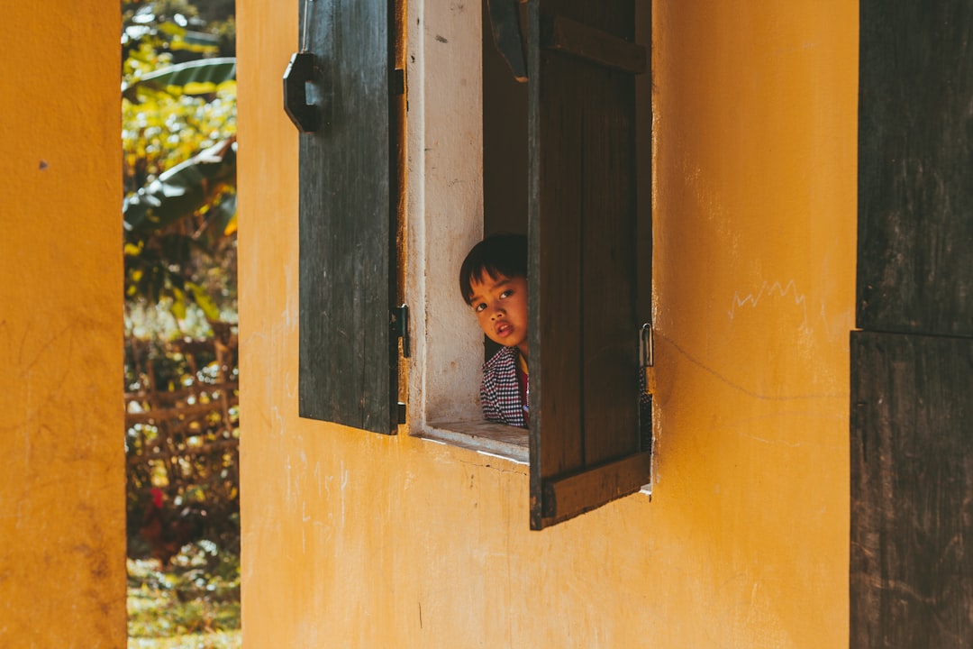 boy in blue shirt climbing on yellow concrete wall