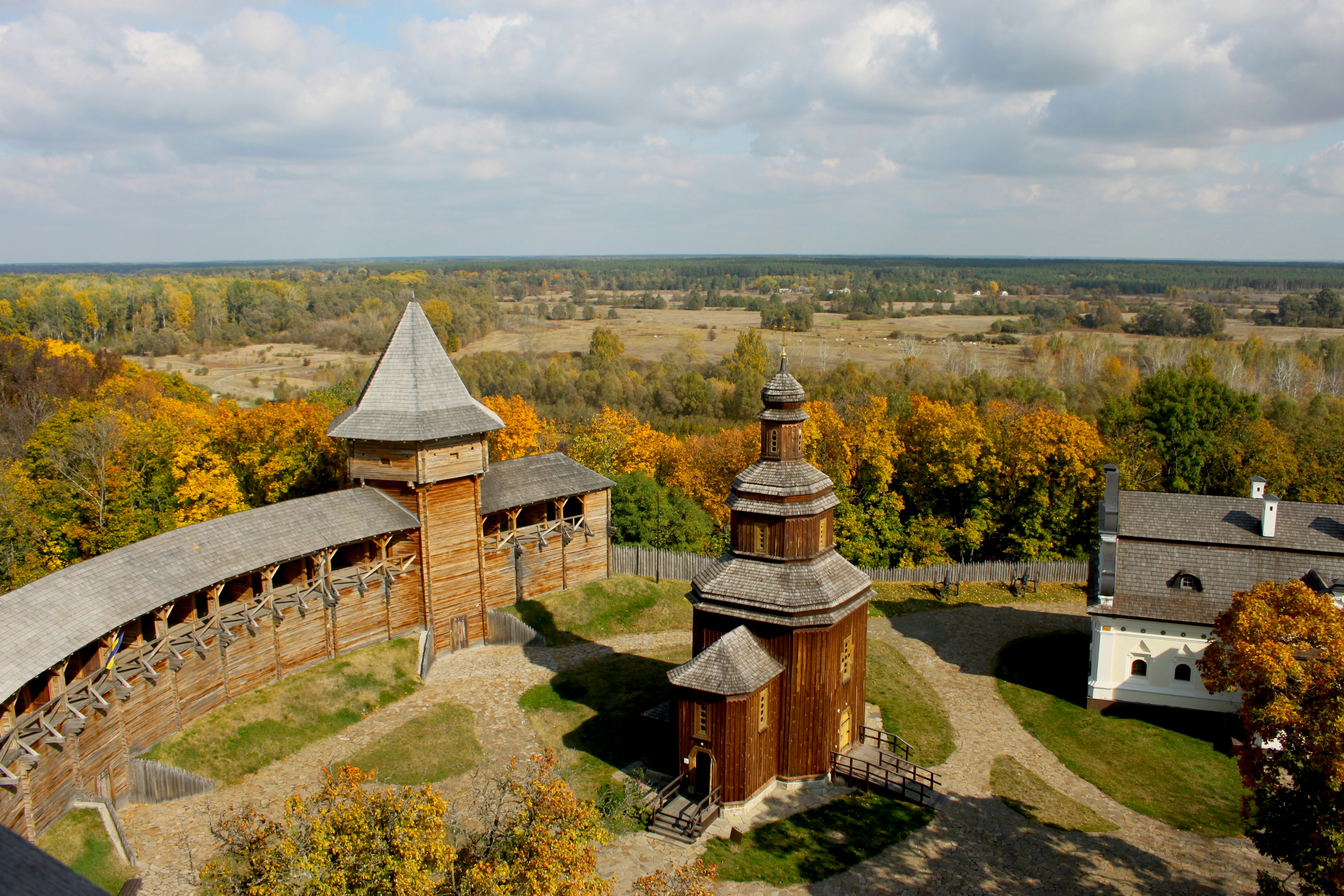 brown and white concrete house on green grass field under white clouds and blue sky during