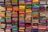 A display of colorful folded fabrics arranged neatly on shelves. The fabrics showcase a variety of patterns and textures, ranging from bright pinks, greens, and blues to intricate embroidery and designs.