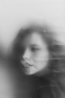 A digital portrait of a person with cool gray and blue tones, featuring subtle pixel effects.