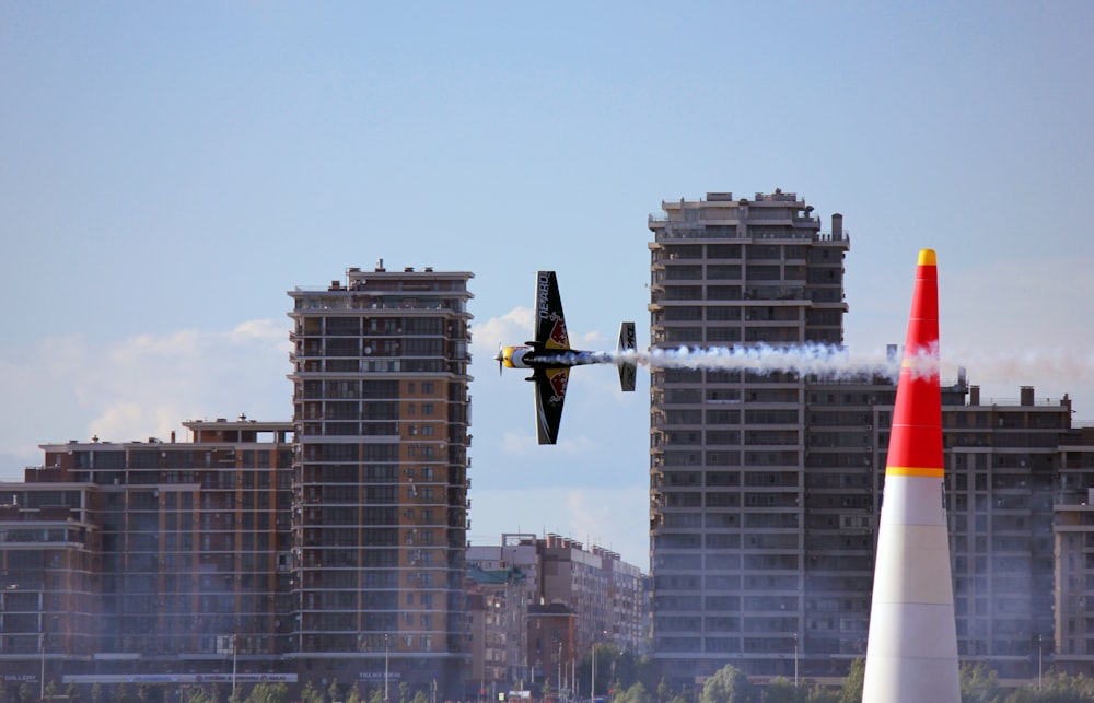 yellow and black plane flying over city buildings during daytime