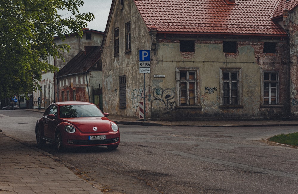 red car parked beside brown concrete building during daytime