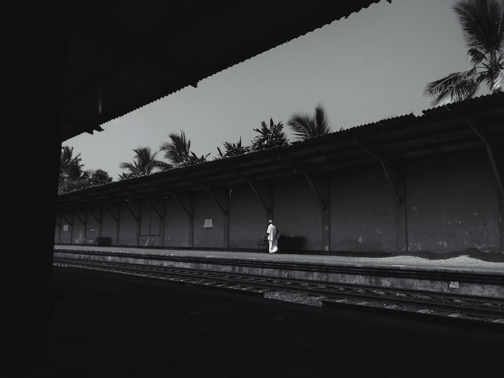기차 레일을 걷는 남자의 그레이스케일 사진