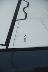A close-up view of an aircraft wing section with visible rivets and panels. The words 'NO STEP' are clearly printed on the wing surface in black lettering.