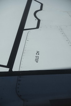 A close-up view of an aircraft wing section with visible rivets and panels. The words 'NO STEP' are clearly printed on the wing surface in black lettering.
