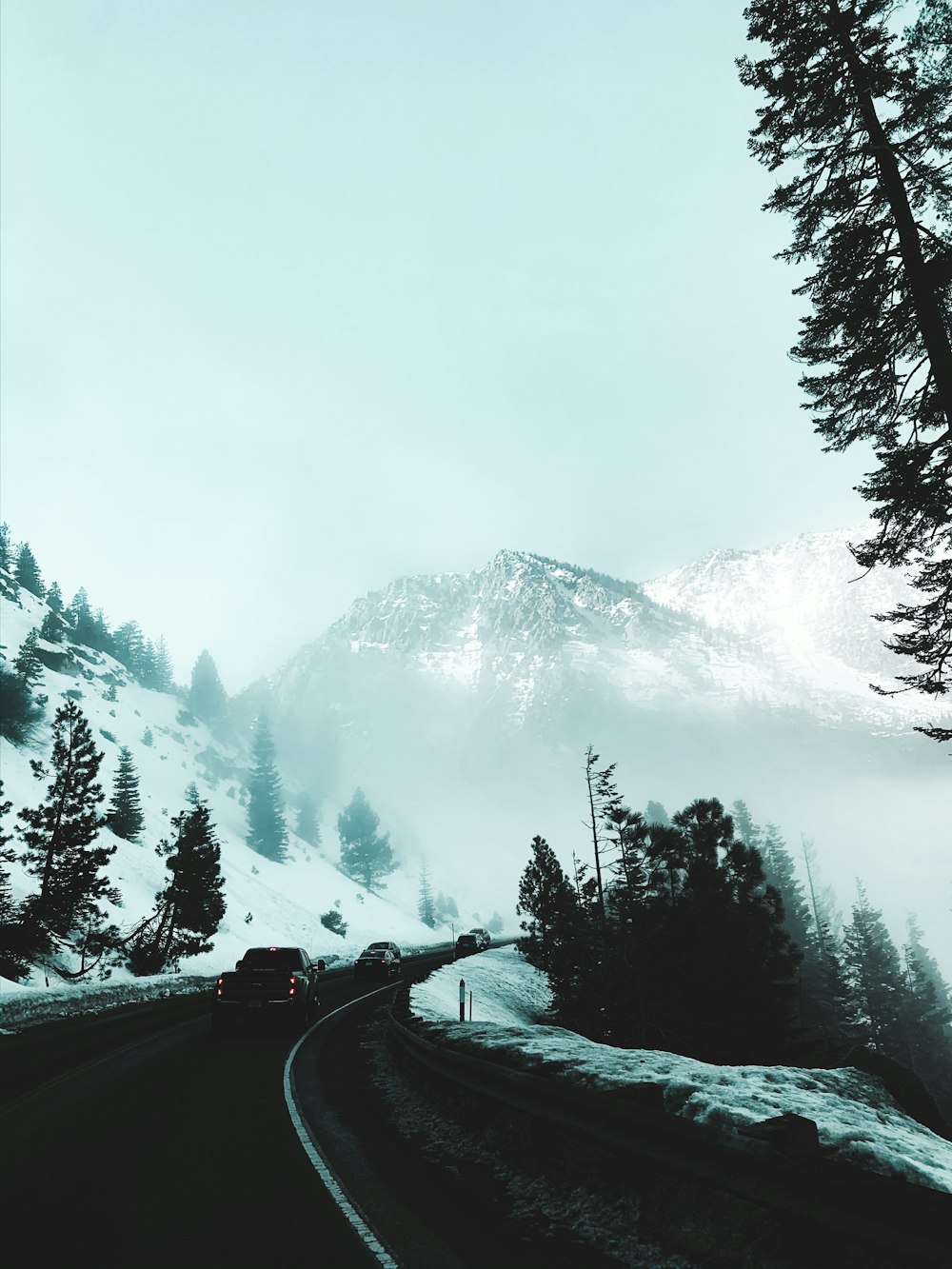 carro preto na estrada perto da montanha coberta de neve durante o dia