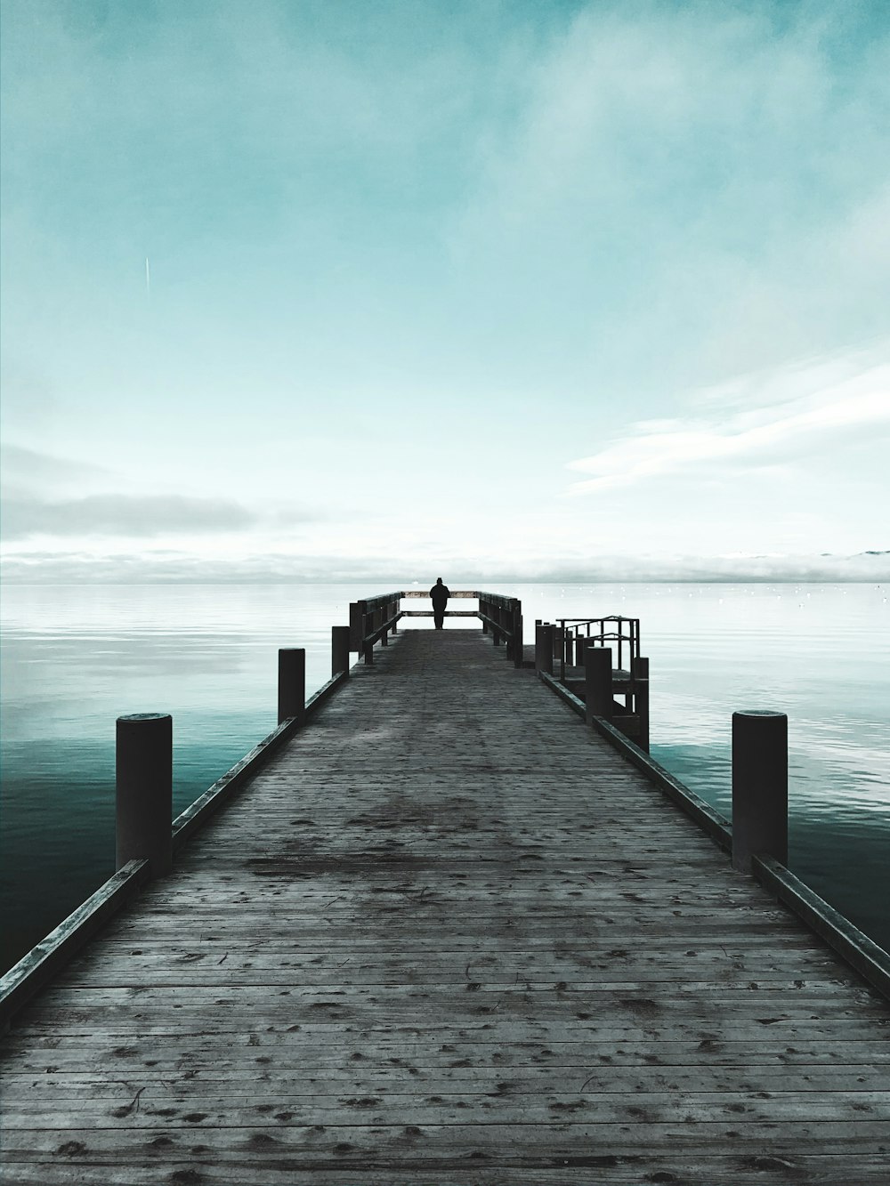 brown wooden dock on sea under white clouds during daytime