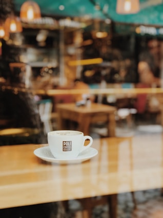 A warm café interior with coffee cups on a wooden table.