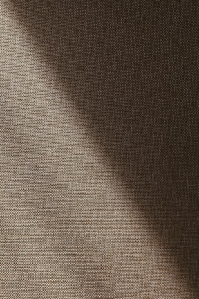 A textured fabric surface with diagonal lighting that creates a gradient of shadows and highlights across the material.