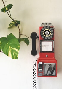 red and black telephone on white wall