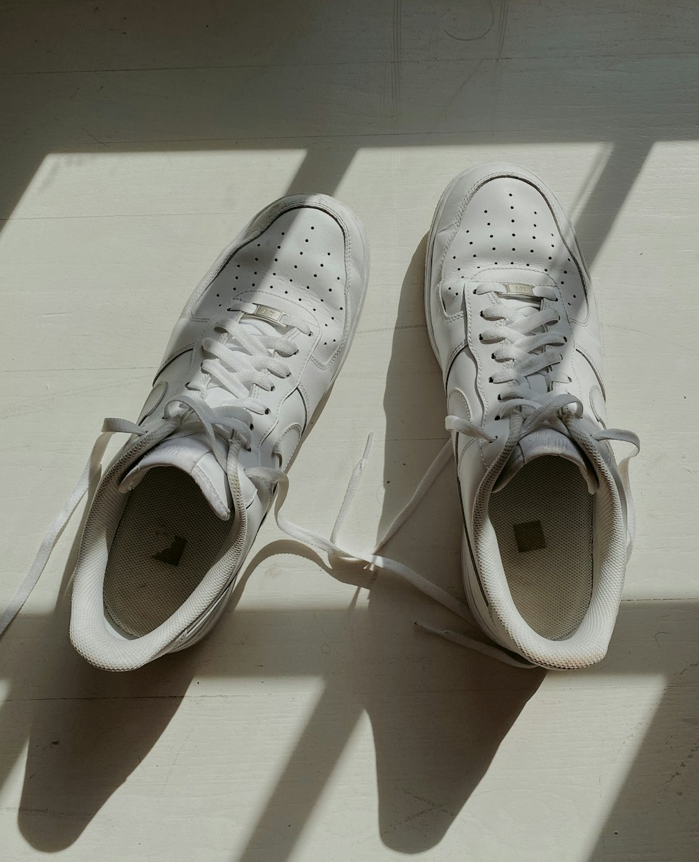 scarpe da ginnastica Nike bianche su tavolo di legno bianco