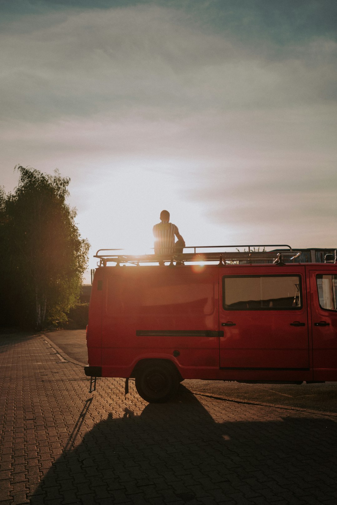 man in white shirt sitting on red van during daytime