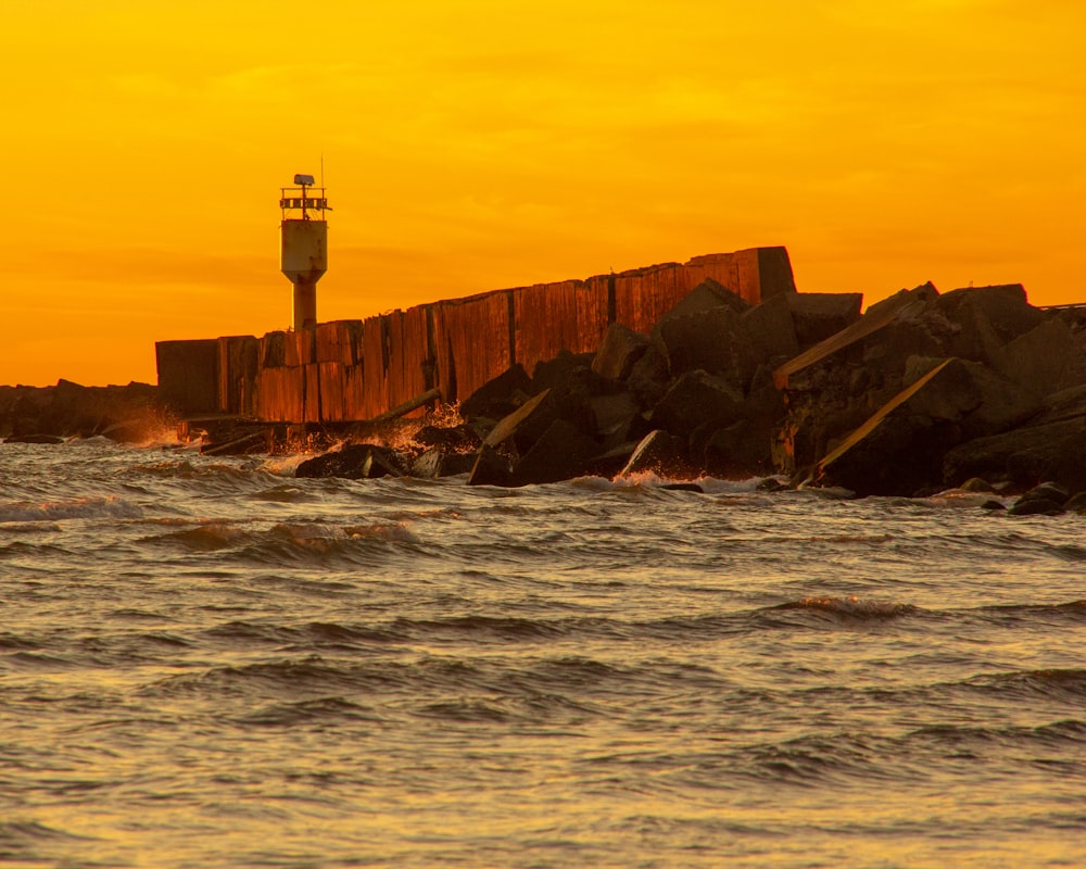 white lighthouse near body of water during sunset