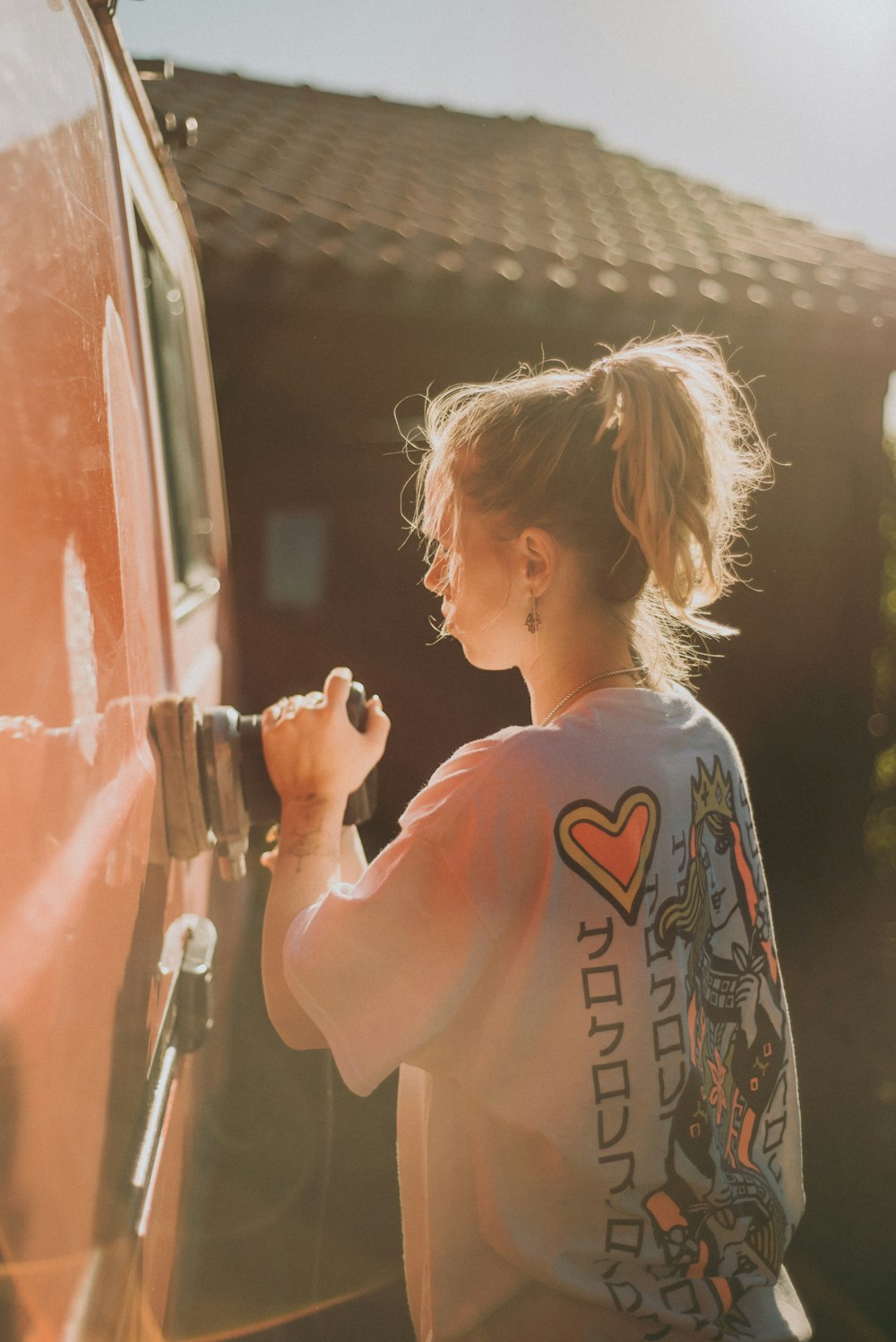 woman in gray and red crew neck t-shirt standing beside red car during daytime