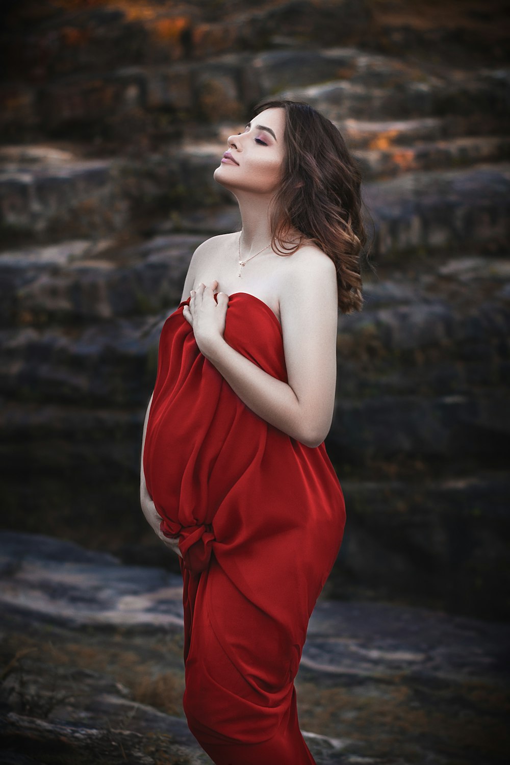 낮 동안 갈색 모래 위에 서 있는 빨간 튜브 드레스를 입은 여자