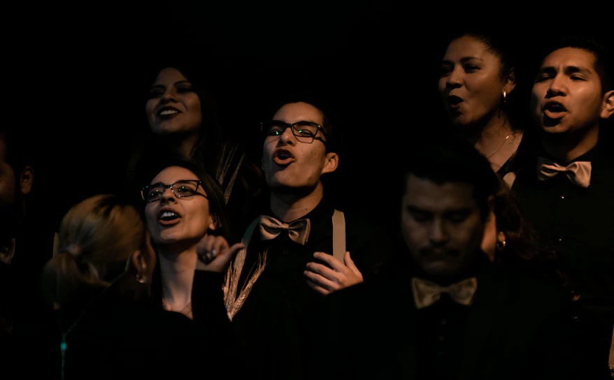 A vibrant group of friends singing passionately in a cozy Studio Six karaoke room with colorful LED lights.