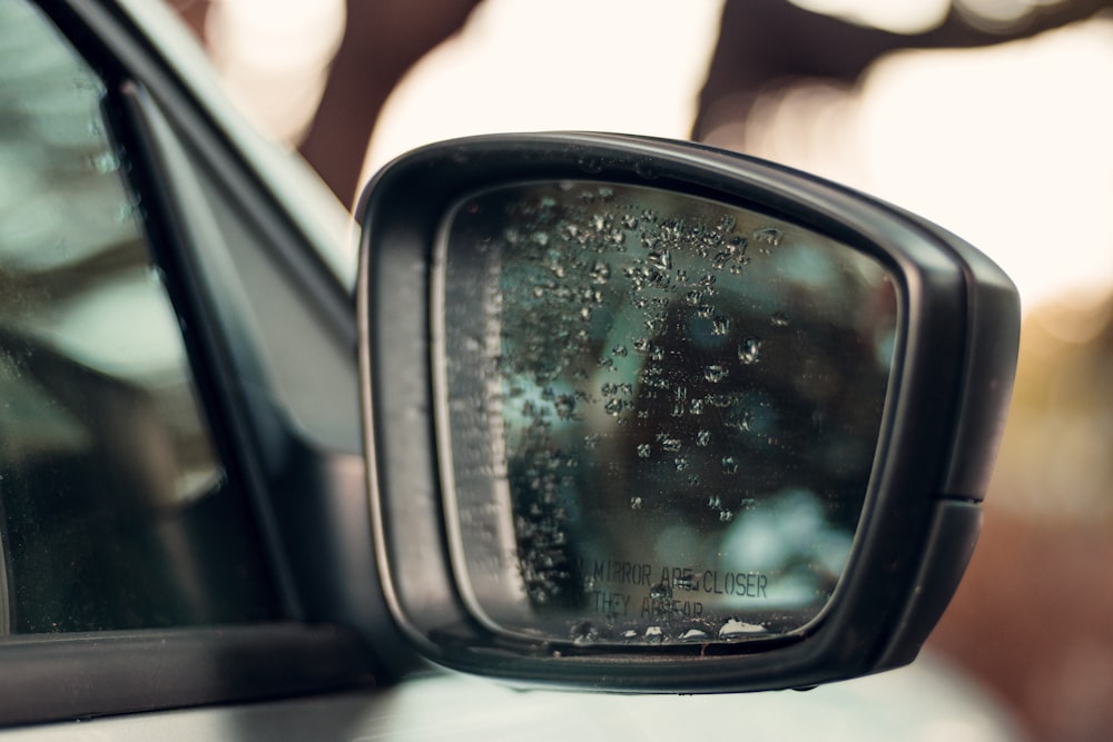 black car side mirror with water droplets