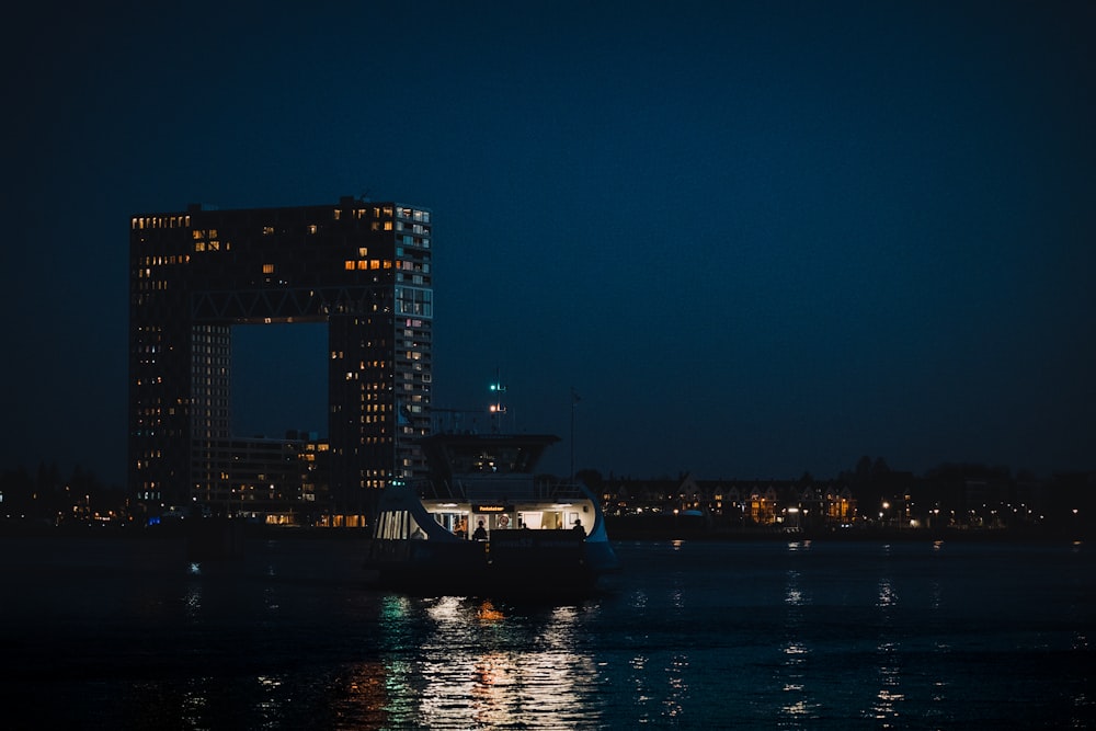 white and black boat on water near city buildings during night time