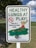 A sign displays the message 'HEALTHY LUNGS AT PLAY' in large green letters, with a no-smoking symbol and a smaller text indicating 'This is a tobacco-free zone.' It includes a cartoon illustration of children playing on a seesaw in a park setting.