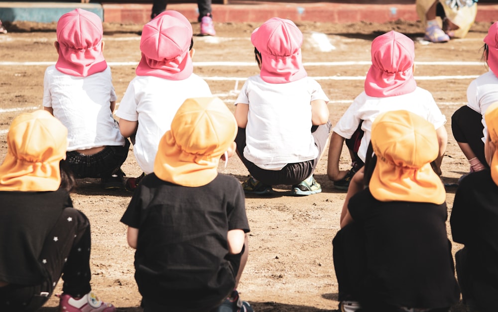 children in black shirt and pink hijab standing on brown sand during daytime