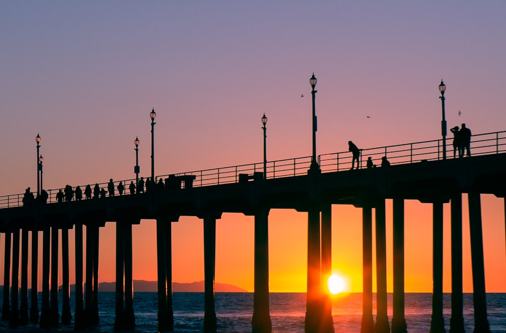 silhouette of person standing on bridge during sunset