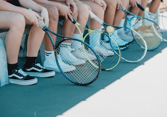 person in black and white nike sneakers holding blue and white tennis racket