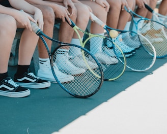 person in black and white nike sneakers holding blue and white tennis racket