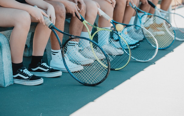 person in black and white nike sneakers holding blue and white tennis racket