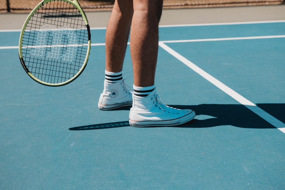 person in white nike sneakers standing on tennis court