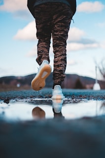 person in black pants and white shoes standing on snow covered ground during daytime