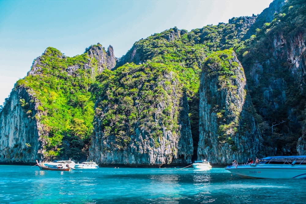 barco branco no mar perto da montanha verde e marrom durante o dia